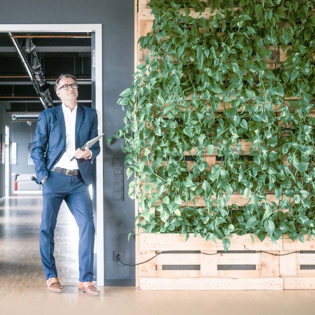 Man in front of office next to green wall 