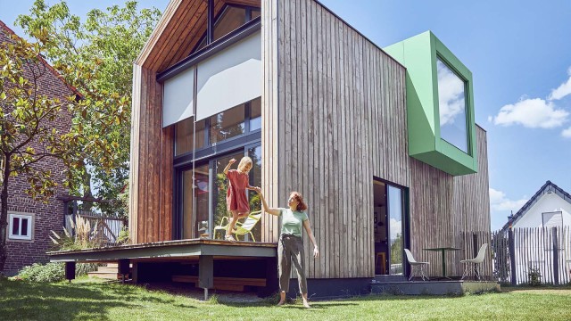 Frau und Kind vor futuristischem Holzhaus