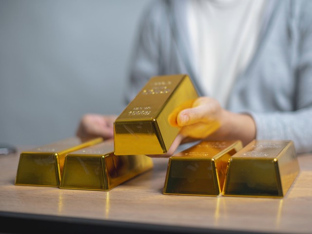 Person h&auml;lt einen Goldbarren