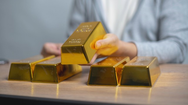Person h&auml;lt einen Goldbarren