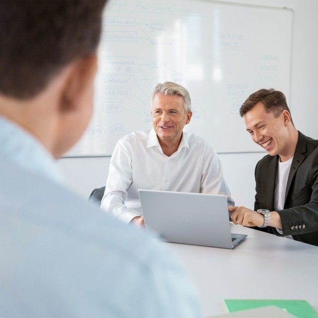 Männer in gemischter Altersgruppe lachend im Meeting