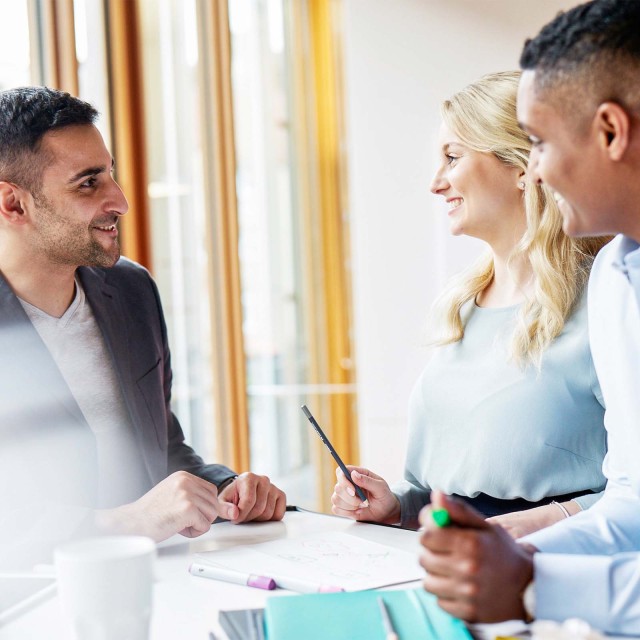 Drei Personen lachend im Büro