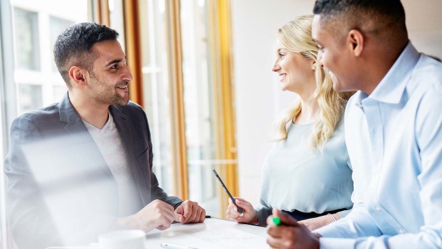 Drei Personen lachend im Büro