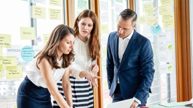 Zwei junge Kolleginnen und ein Kollege sprechen gemeinsam über Projekt