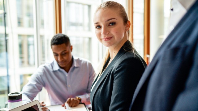 Frau in Business Kleidung schaut selbstbewusst in die Kamera