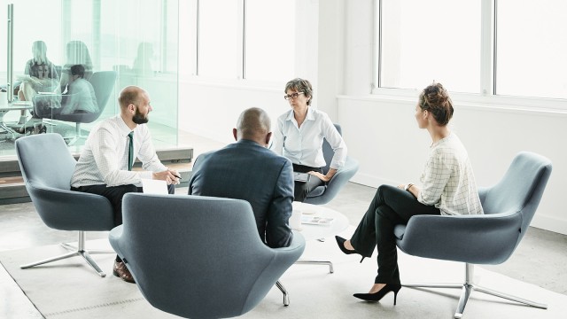 Four people in an armchair, talking