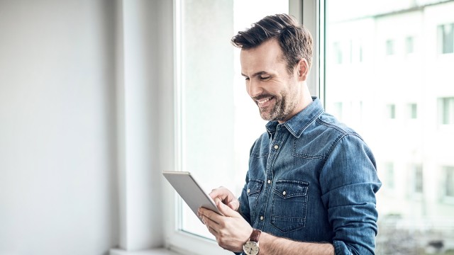 Lächelnder Mann blickt auf sein Tablet