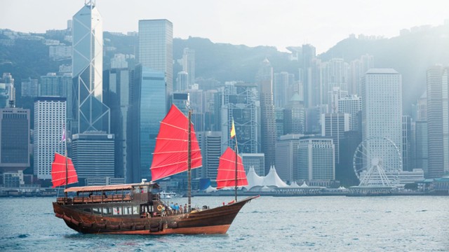 Ein Schiff fährt an einer chinesischen Stadt vorbei.