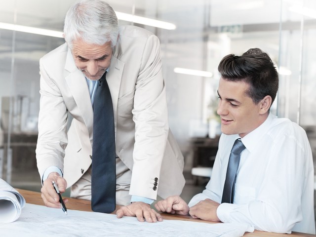 Zwei M&auml;nner die an einem Tisch sitzen und etwas besprechen