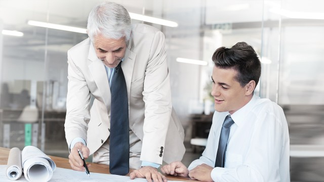 Zwei Männer die an einem Tisch sitzen und etwas besprechen