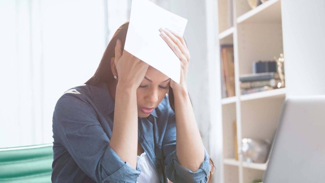 Eine Frau sitzt am Tisch und berechnet verzweifelt ihren Gewinn und ihre Ausgaben