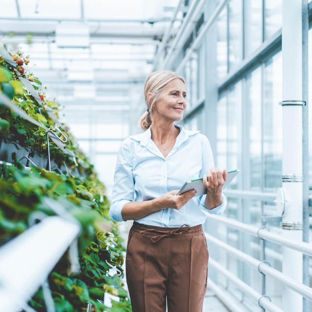 Woman goes through green planted glass building