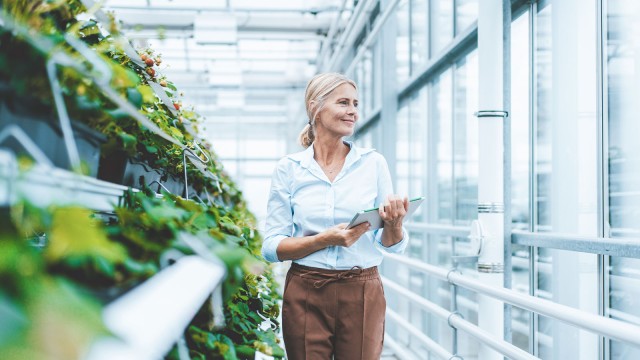 Woman goes through green planted glass building