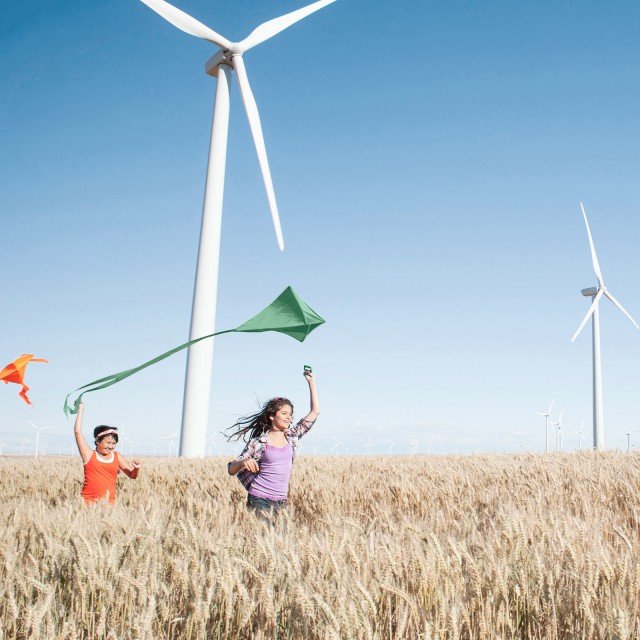 Children running in the fields in front of windmills