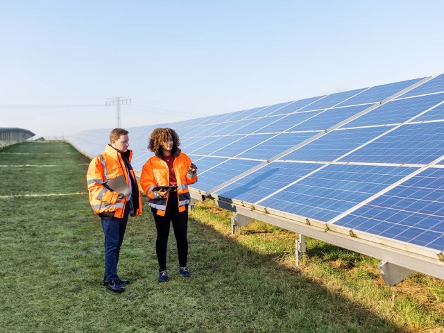 Zwei Arbeiter stehen vor einer Photovoltaik Anlage