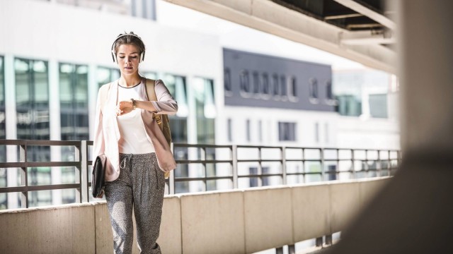Young businesswoman walks in the parking garage and looks at her watch