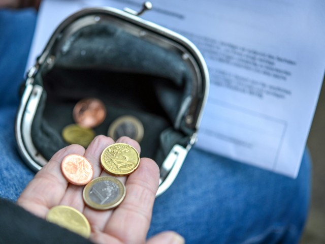 Arme ältere Frau zählt einige Euro und Cents Münzen in der Hand