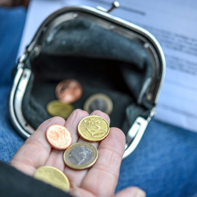 Arme ältere Frau zählt einige Euro und Cents Münzen in der Hand