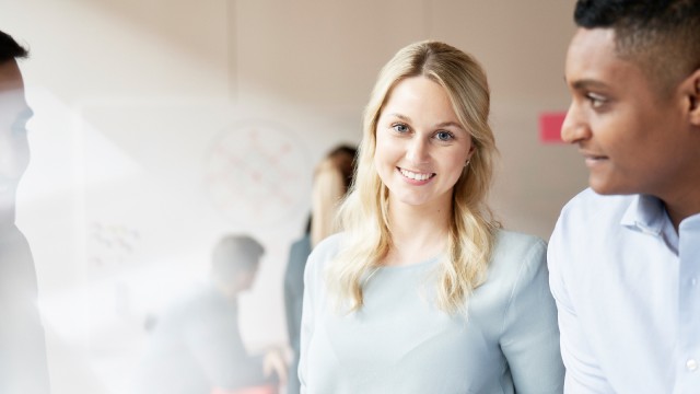 Eine lächelnde blonde Frau und ein Mann neben ihr