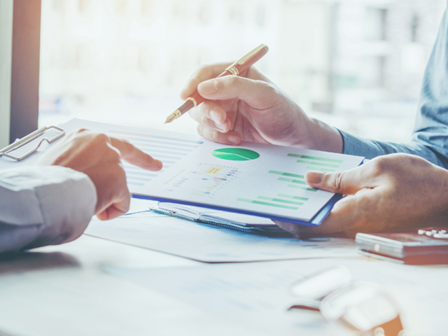 Geschäftsleute diskutieren Grafiken am Schreibtisch im Meeting