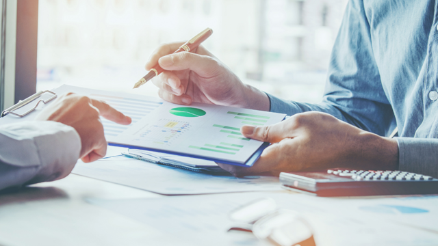 Geschäftsleute diskutieren Grafiken am Schreibtisch im Meeting