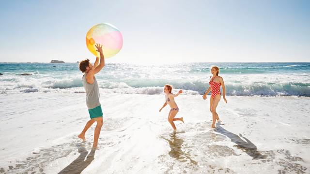 Familie spielt am Strand Wasserball