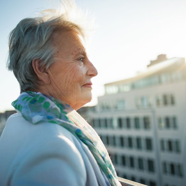 Ältere Dame steht auf Dachterrasse