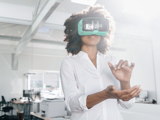 Frau mit VR-Brille hebt die Hände hoch