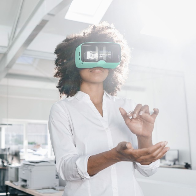 Frau mit VR-Brille hebt die Hände hoch