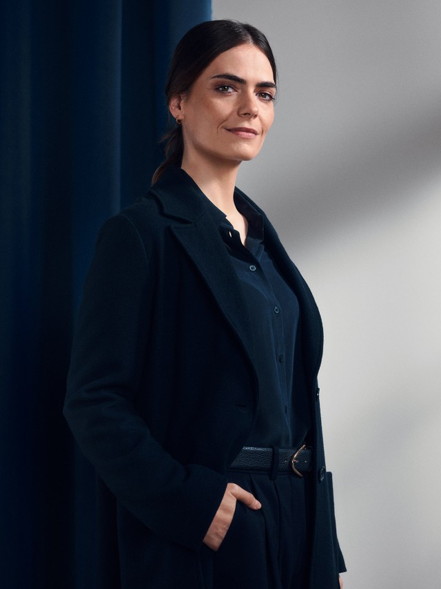 Eine Frau steht neben einem blauem Hintergrund „„Symbolbild zur Imagekampagne Nur Mut“