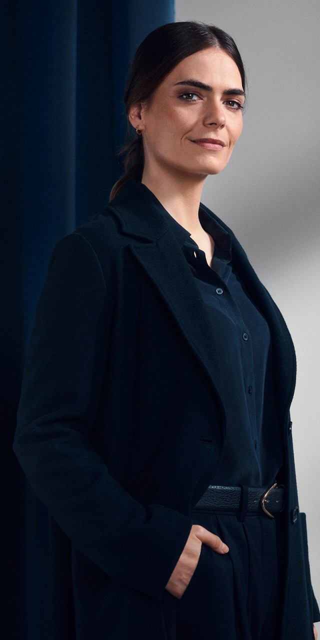 Eine Frau steht neben einem blauem Hintergrund „„Symbolbild zur Imagekampagne Nur Mut“