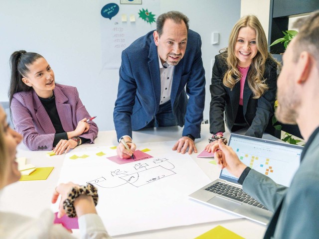 Drei Menschen arbeiten an einem Plakat