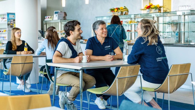 Drei Personen im Gespräch in einer Kantine