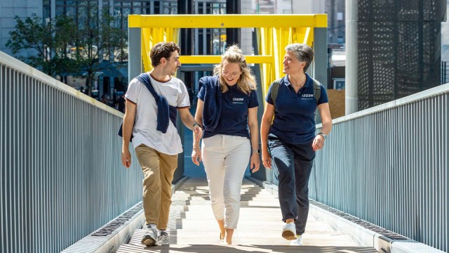 Drei Menschen sind unterwegs auf einer gelben Brücke