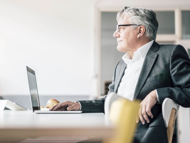 Mann vor Laptop schaut zufrieden 