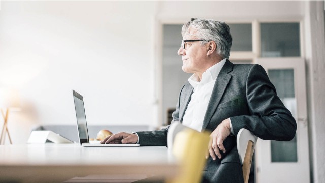 Mann vor Laptop schaut zufrieden 