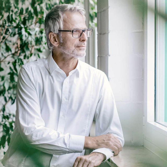 Man standing in front of a green wall is watching outside