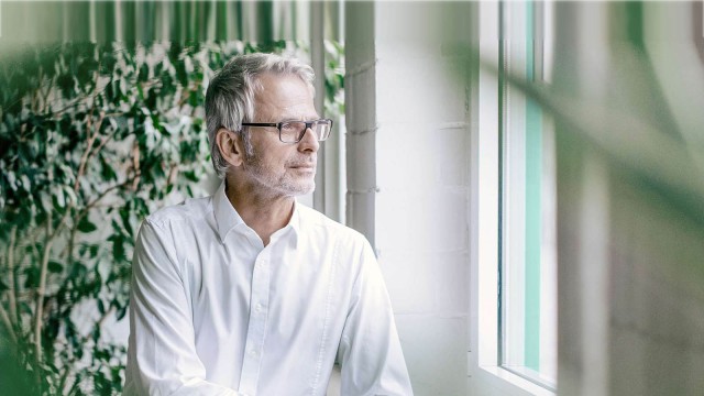 Man standing in front of a green wall is watching outside