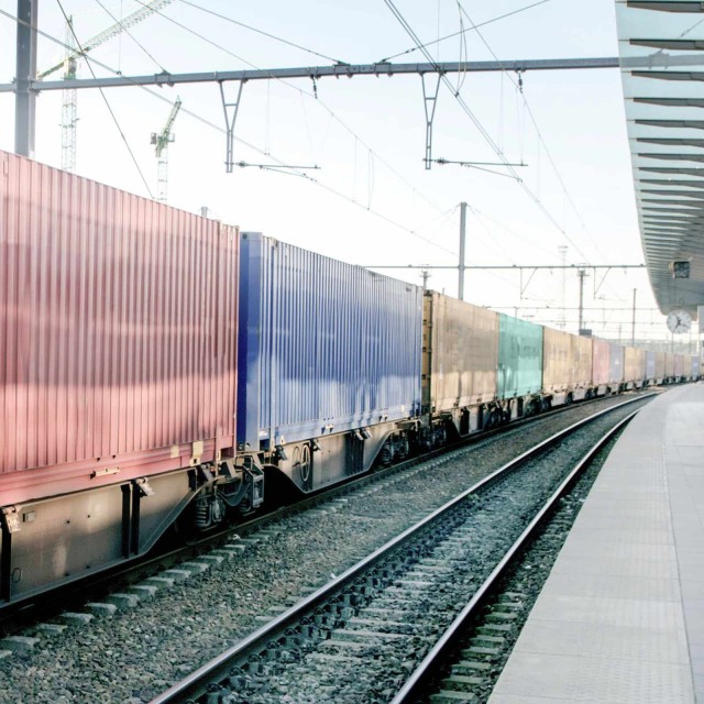 Zug mit Containern rollt am Bahnhof vorbei 