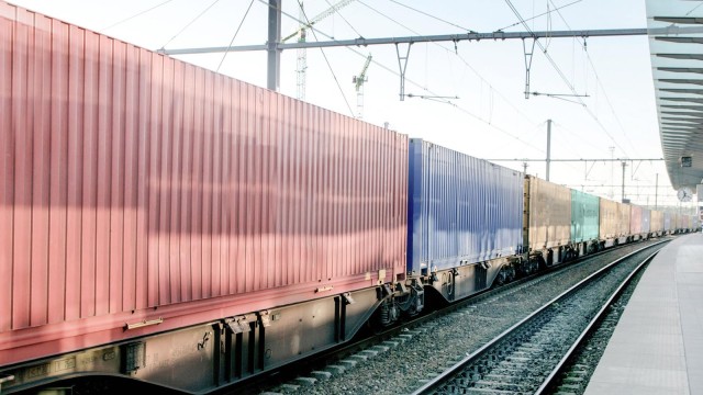 Zug mit Containern rollt am Bahnhof vorbei 