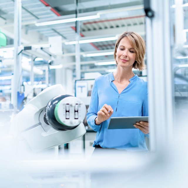 Frau mit Notebook in Produktionsanlage 