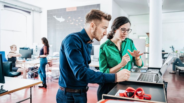 Junger Mann und junge Frau sprechen miteinander in einem Start-up