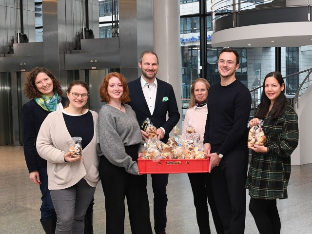 Sozial Aktion in der LBBW, Mitarbeitende stehen mit selbstgebackenen Plätzchen vor Weihnachtsbaum