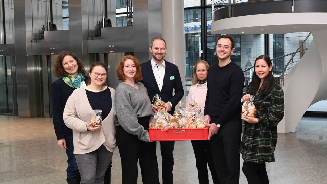 Sozial Aktion in der LBBW, Mitarbeitende stehen mit selbstgebackenen Plätzchen vor Weihnachtsbaum