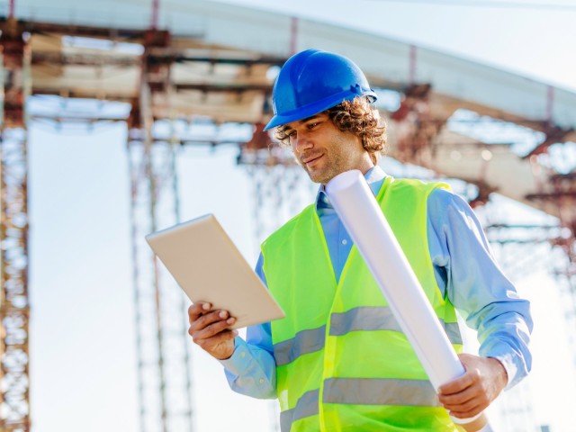 Ingenieur auf Baustelle mit digitalen Blaupausen