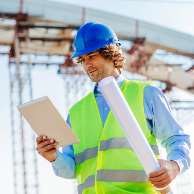 Ingenieur auf Baustelle mit digitalen Blaupausen