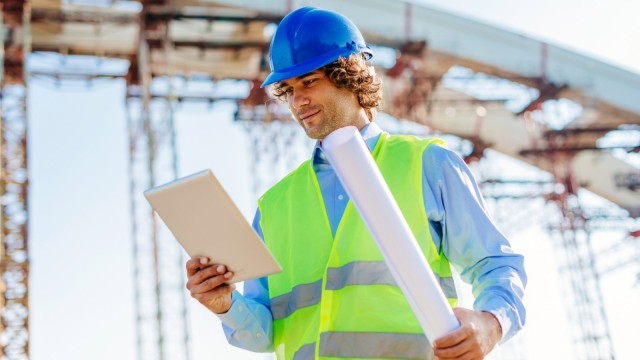 Ingenieur auf Baustelle mit digitalen Blaupausen