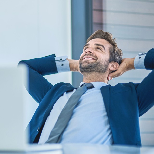 Ein Mann sitzt gemütlich zurückgelehnt am Arbeitsplatz