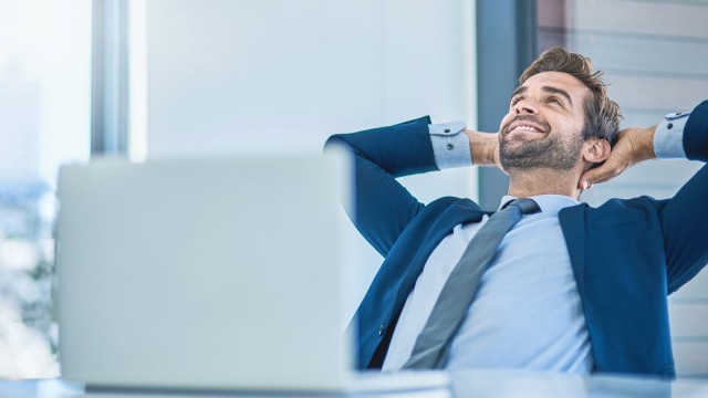 Ein Mann sitzt gemütlich zurückgelehnt am Arbeitsplatz