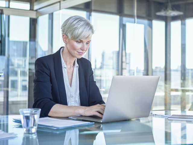 Business-Frau sitzt am Schreibtisch und arbeitet am Laptop